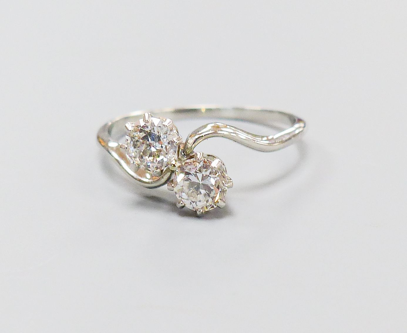 A white metal and two stone diamond set crossover ring, size K, gross 2.4 grams